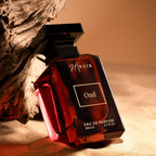 Perfume bottle labeled 'Ninior Oud' on a textured surface with warm lighting