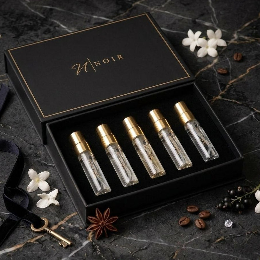 Set of LUXURY OUD perfume bottles in a black box with Noir' branding on a dark marble surface.