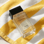 Perfume bottle labeled 'Essentials Sport' on a yellow and white striped fabric background