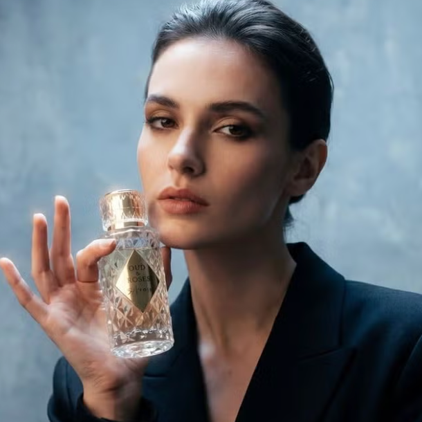 Woman holding a perfume bottle against a gray background